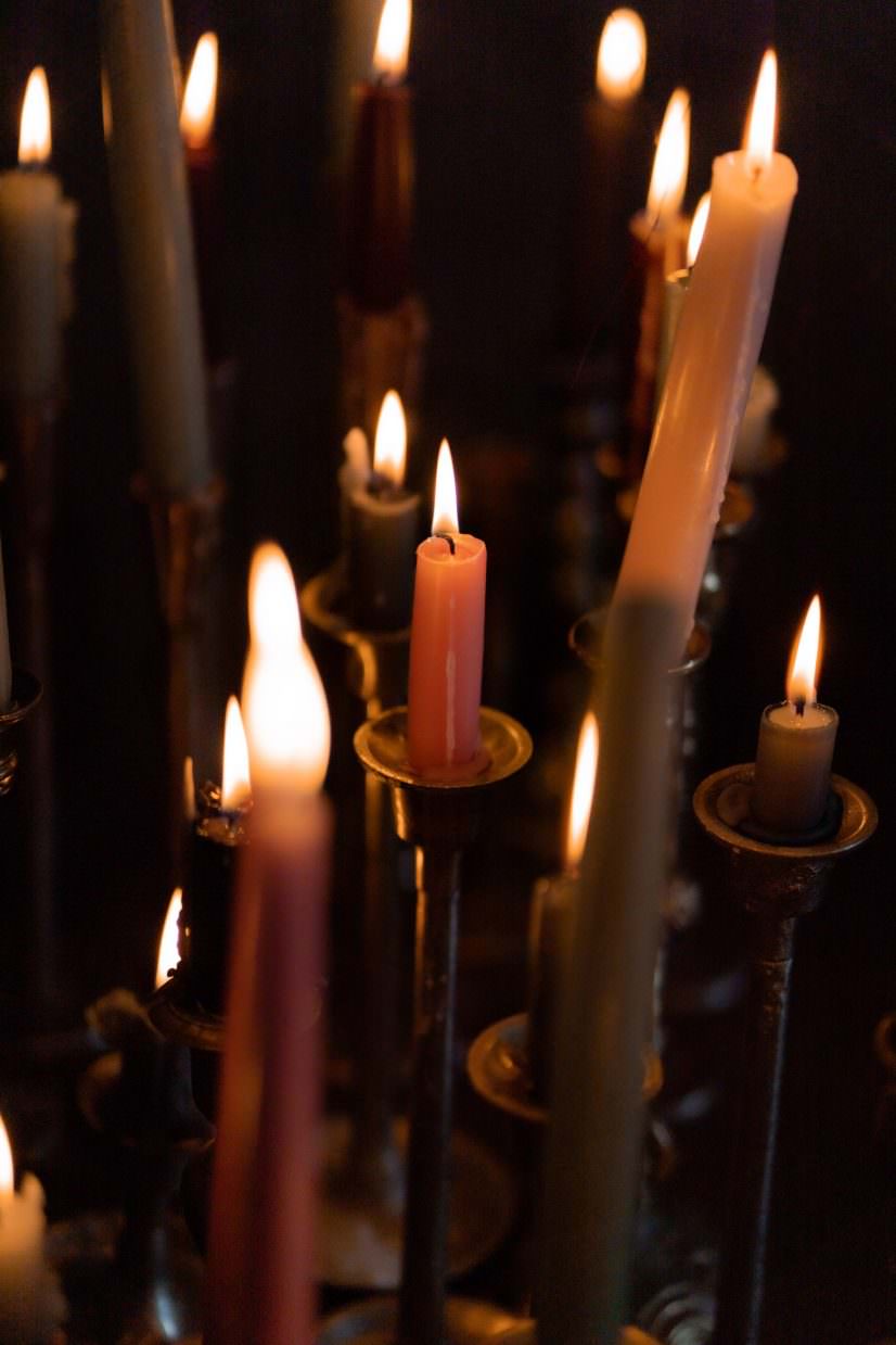 Tall candles burning in a dark interior